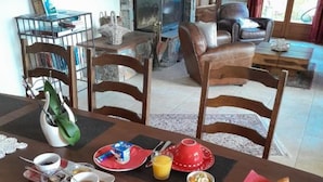A dining table set with breakfast items, a fireplace, and a view of the outdoors. - Villa 10 Personnes au Calme Entre mer et Montagne. 5 Chambres, 5 Salles de Bain (Vico)