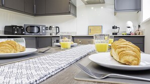 A breakfast setup with croissants, orange juice, and a coffee maker in a modern kitchen.