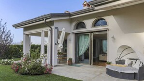 A modern house with a covered patio, a garden with flowers, and a bed with a canopy. - Villa with private pool in The Tuscan Countryside (Figline e Incisa Valdarno)