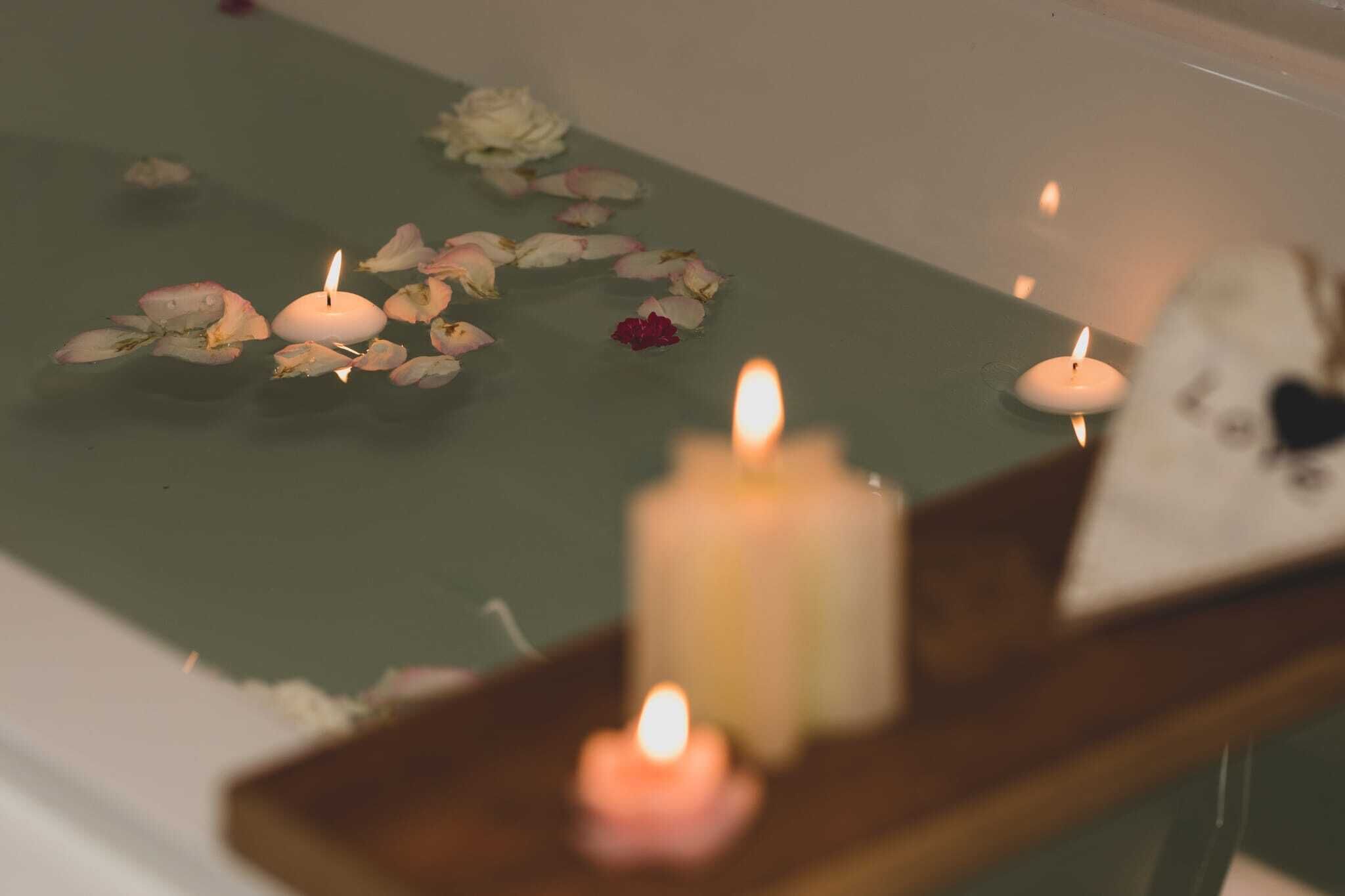 A candlelit table with a tray, surrounded by rose petals.