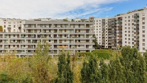 Un immeuble résidentiel à plusieurs étages, doté de balcons et entouré de verdure.