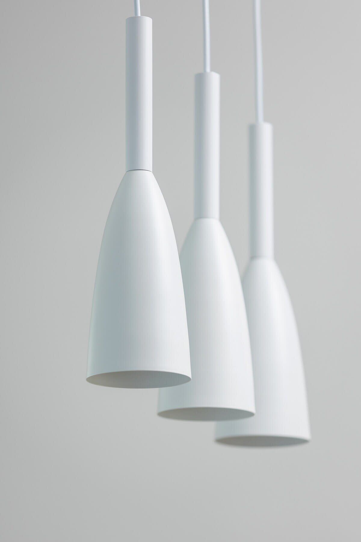 Trois suspensions blanches sont suspendues au plafond.