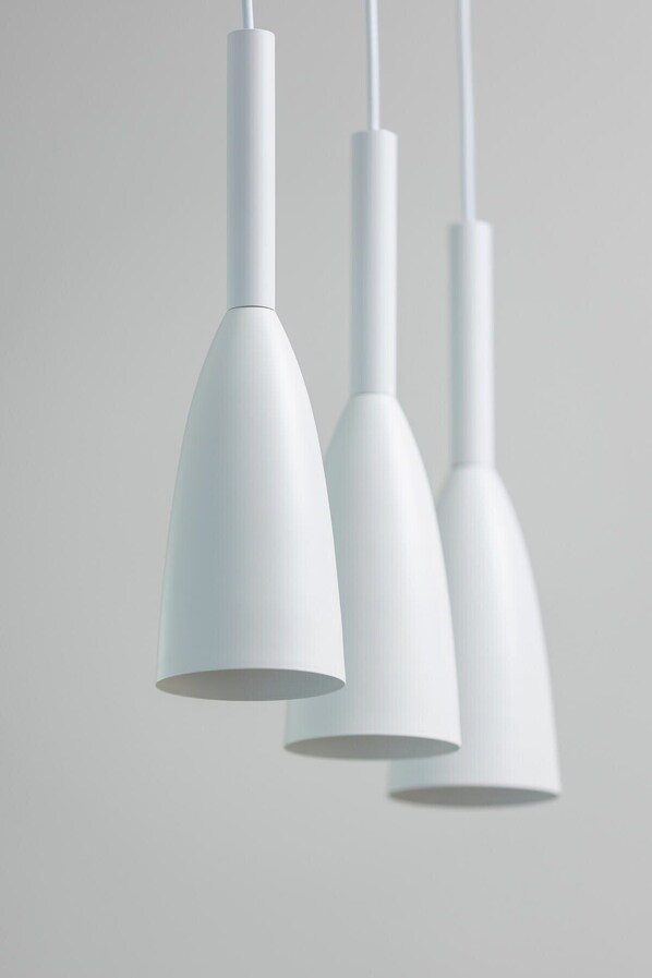 Trois suspensions blanches sont suspendues au plafond.