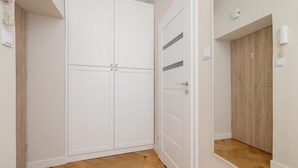 A hallway with a white wardrobe, a wooden door, and a light switch on the wall. - Modern Studio in Kazimierz | 1 km from the Wawel Castle (Kraków)