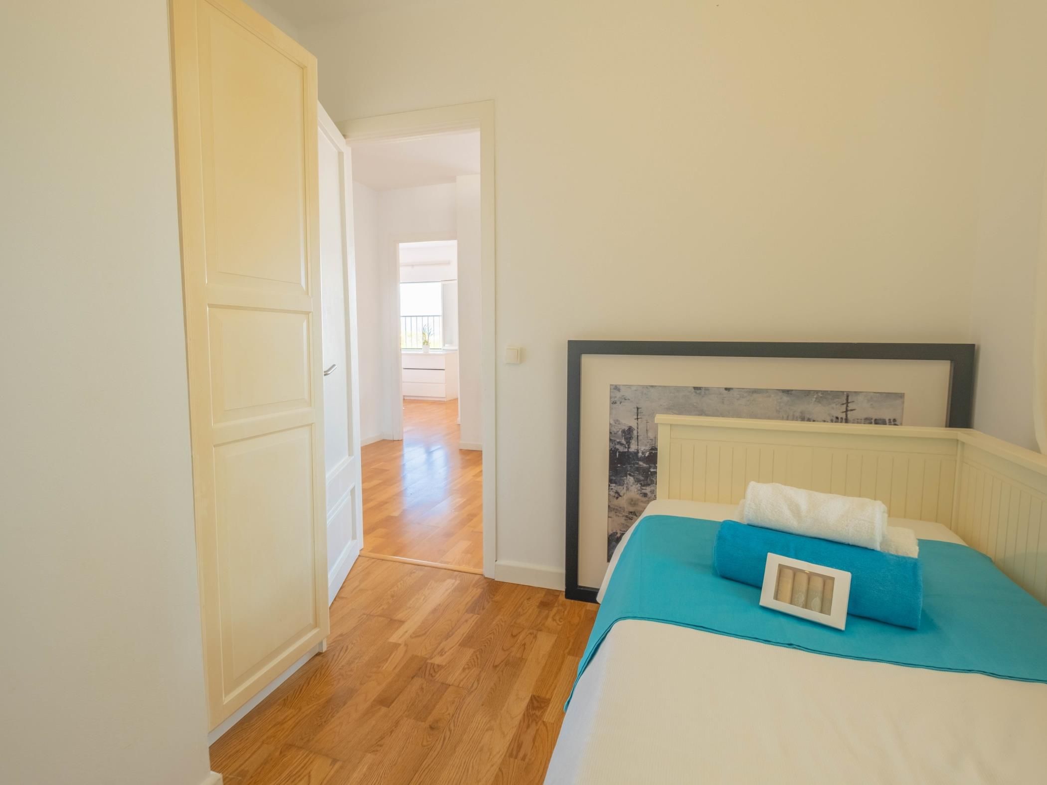 Quarto com cama, porta e corredor que dá para outro cômodo.