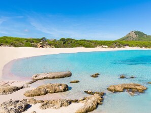 A beach with clear turquoise water, white sand, and rocky outcrops. - Apartamento Bonaire · Your beachfront apartment in Alcúdia. (Alcúdia)