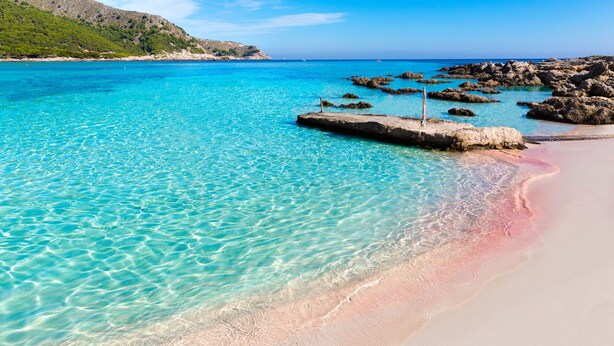 A clear turquoise sea with a rocky outcrop and a sandy beach. - Apartamento Bonaire (Alcúdia)