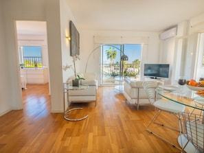 A modern living room with a glass coffee table, white sofas, and a TV. - Apartamento Bonaire · Your beachfront apartment in Alcúdia. (Alcúdia)
