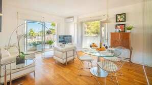 A modern living room with a glass dining table, white sofas, and a TV. - Apartamento Bonaire (Alcúdia)