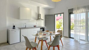 A modern kitchen with white cabinets, a built-in oven, and a dining area with a table and chairs. - Beach front home in Vasilika Evia (Vasilika Evia)
