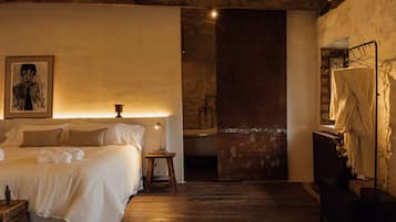 A cozy bedroom with a bed, bedside table, lamp, and a framed picture on the wall.