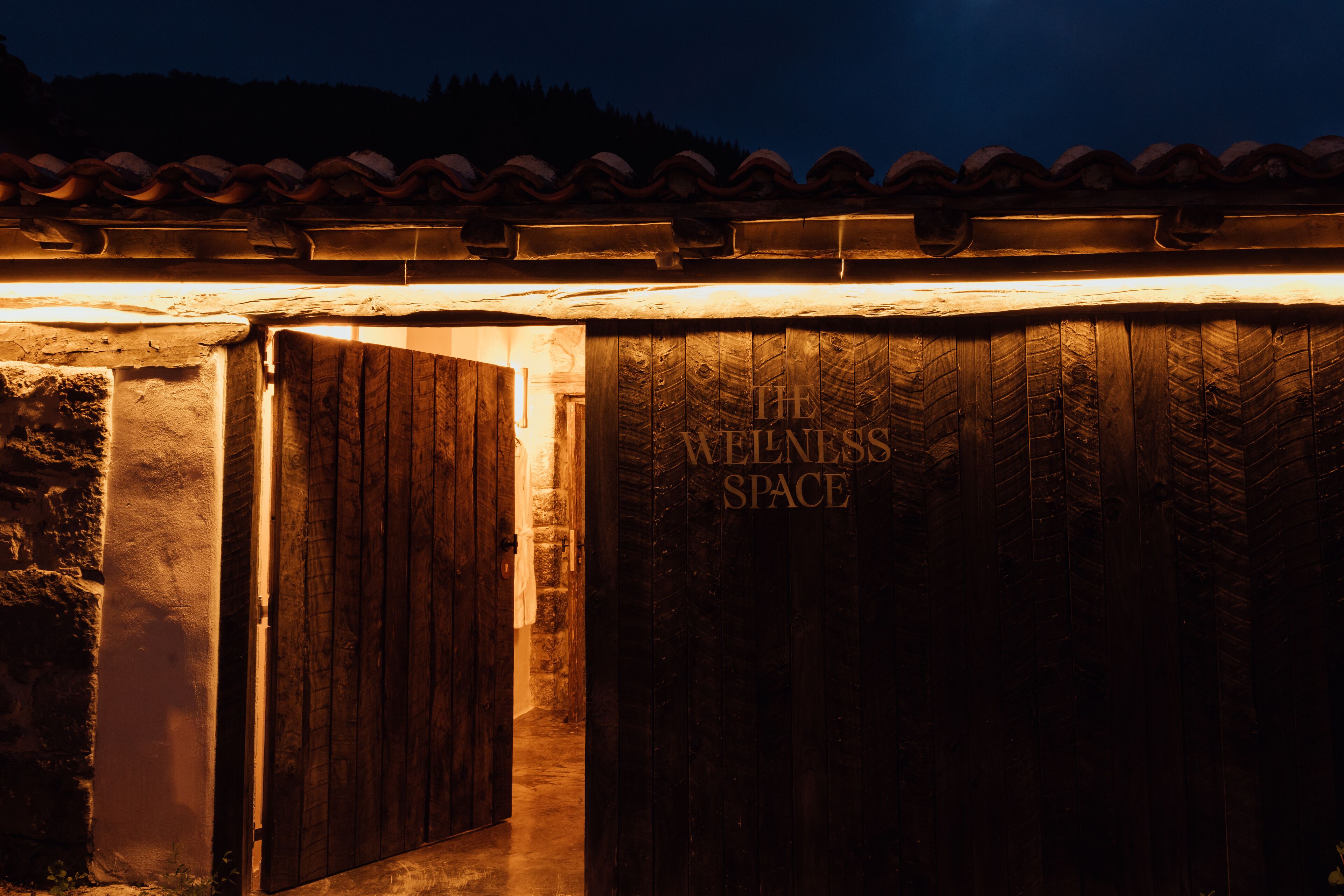 Une porte en bois portant l’inscription « Espace bien-être », éclairée d’une lumière chaleureuse.