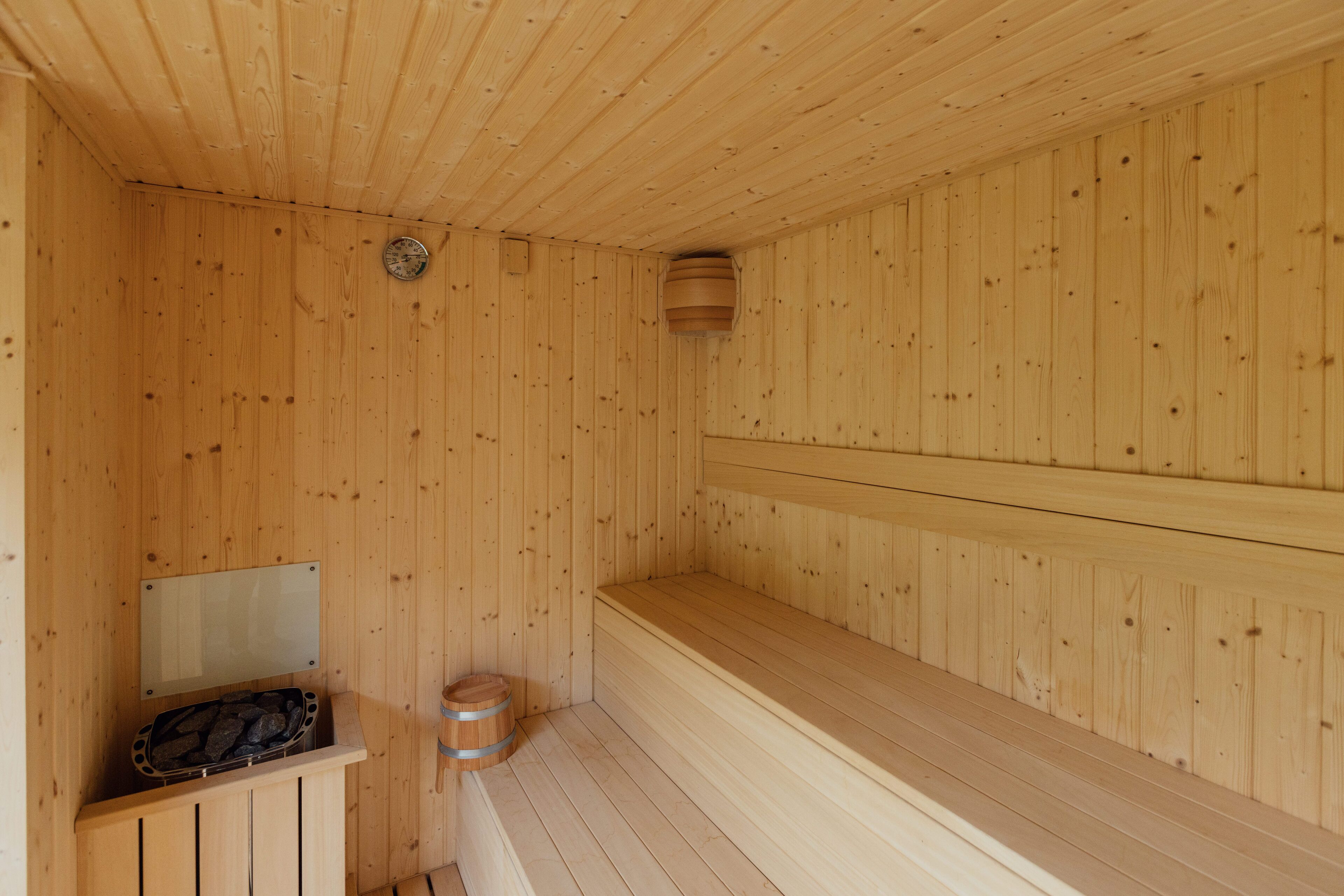 A wooden sauna with benches and a bench seat, a wooden bench, and a small wooden stool.