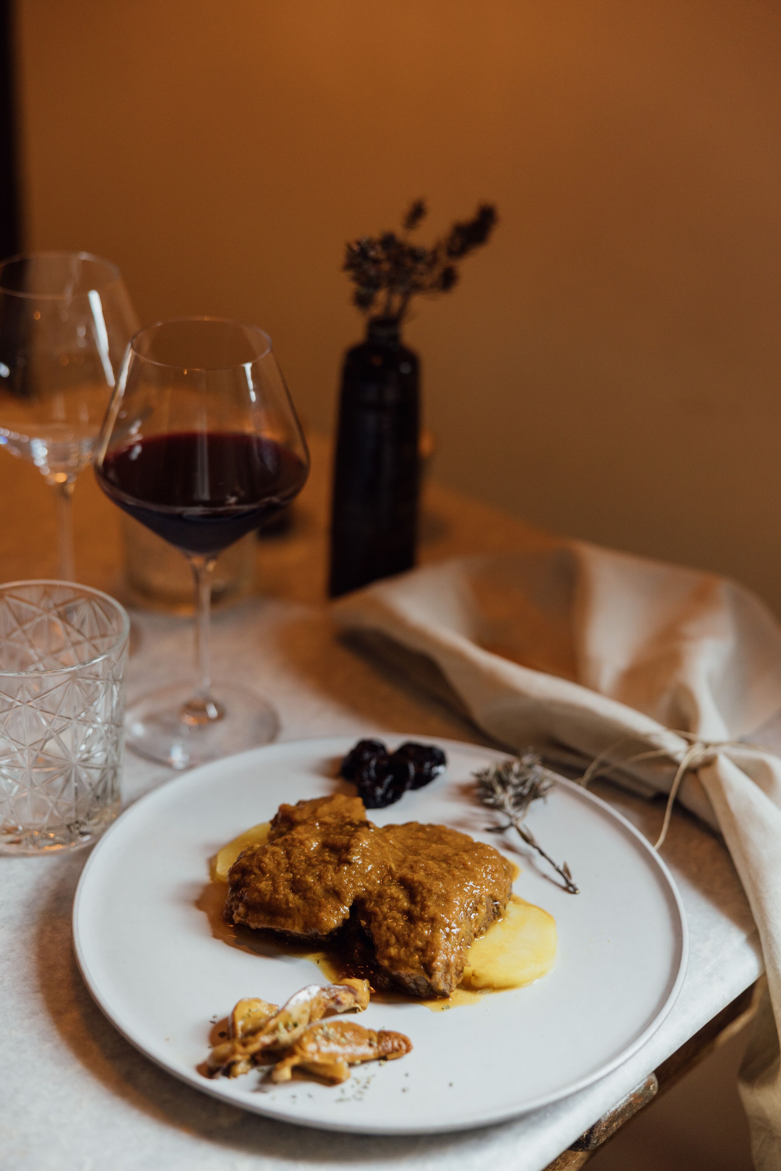 Prato com comida e um copo de vinho tinto sobre uma mesa.