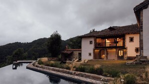 Een villa met een zwembad, een houten terras en een pad van stenen.