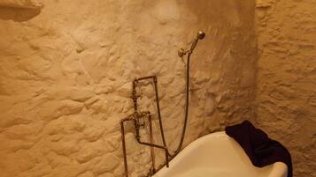 Una bañera en una habitación con paredes texturizadas y suelo de madera.