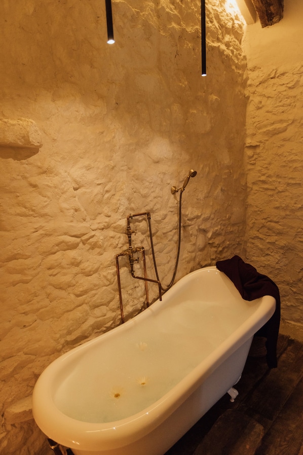 Una bañera en una habitación con paredes texturizadas y suelo de madera.