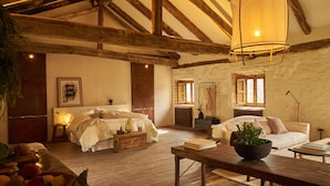 Een rustieke slaapkamer met een houten plafond, een bed, een nachtkastje en een raam met gordijnen.