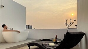A modern bathroom with a bathtub and a lounge chair. - Your Local Spacious 3-story Home, Rooftop views & King Beds near Night Bazaar (Chang Wat Chiang Mai)