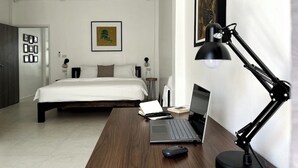 A hotel room with a bed, a desk with a laptop, a desk lamp, and a framed picture on the wall. - Your Local Spacious 3-story Home, Rooftop views & King Beds near Night Bazaar (Chang Wat Chiang Mai)