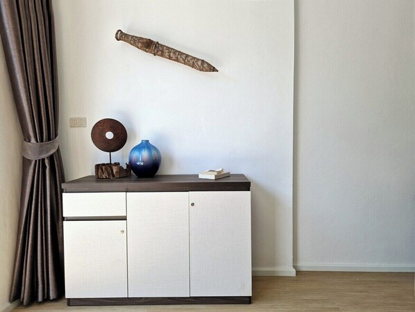 Une pièce au décor minimaliste, avec un meuble blanc, un vase bleu et un élément décoratif accroché au mur.