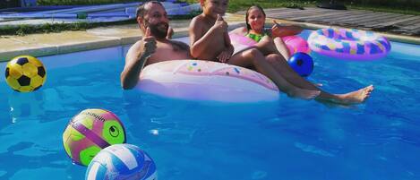 A swimming pool with inflatable rings and a soccer ball.