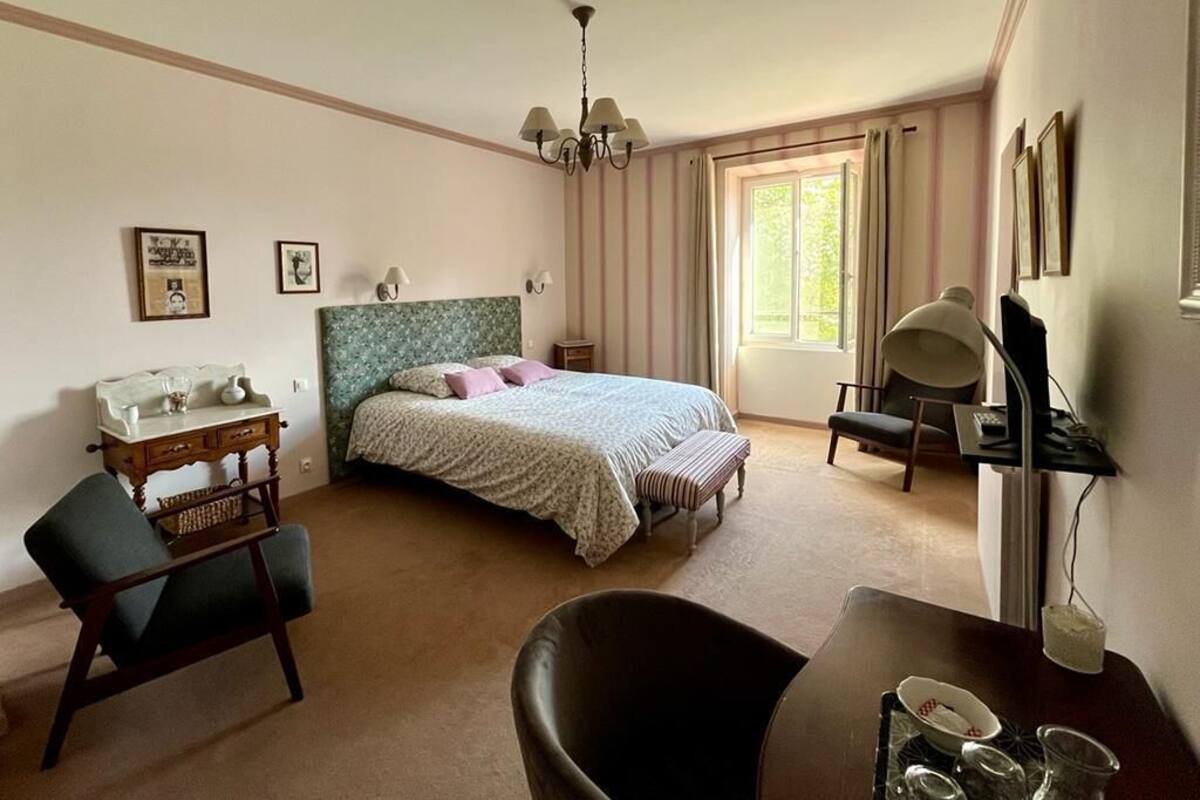A bedroom with a bed, a desk, a chair, a dresser, and a window with curtains.