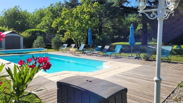 A wooden deck with a pool, lounge chairs, and a small shed. - Le cèdre bleu (Saint-Lattier)