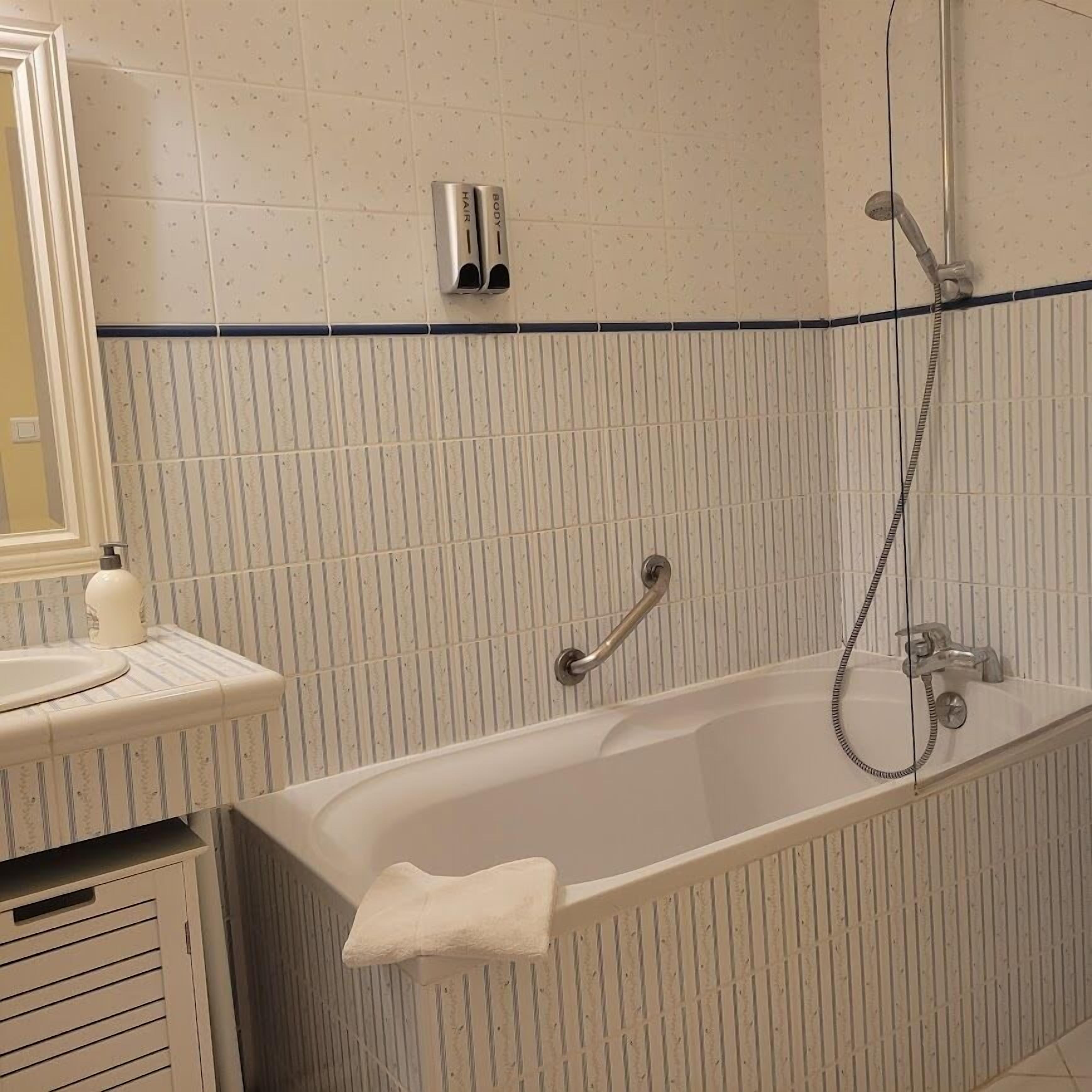 Une salle de bain équipée d’une baignoire, d’un lavabo, d’un miroir et d’un porte-serviettes.
