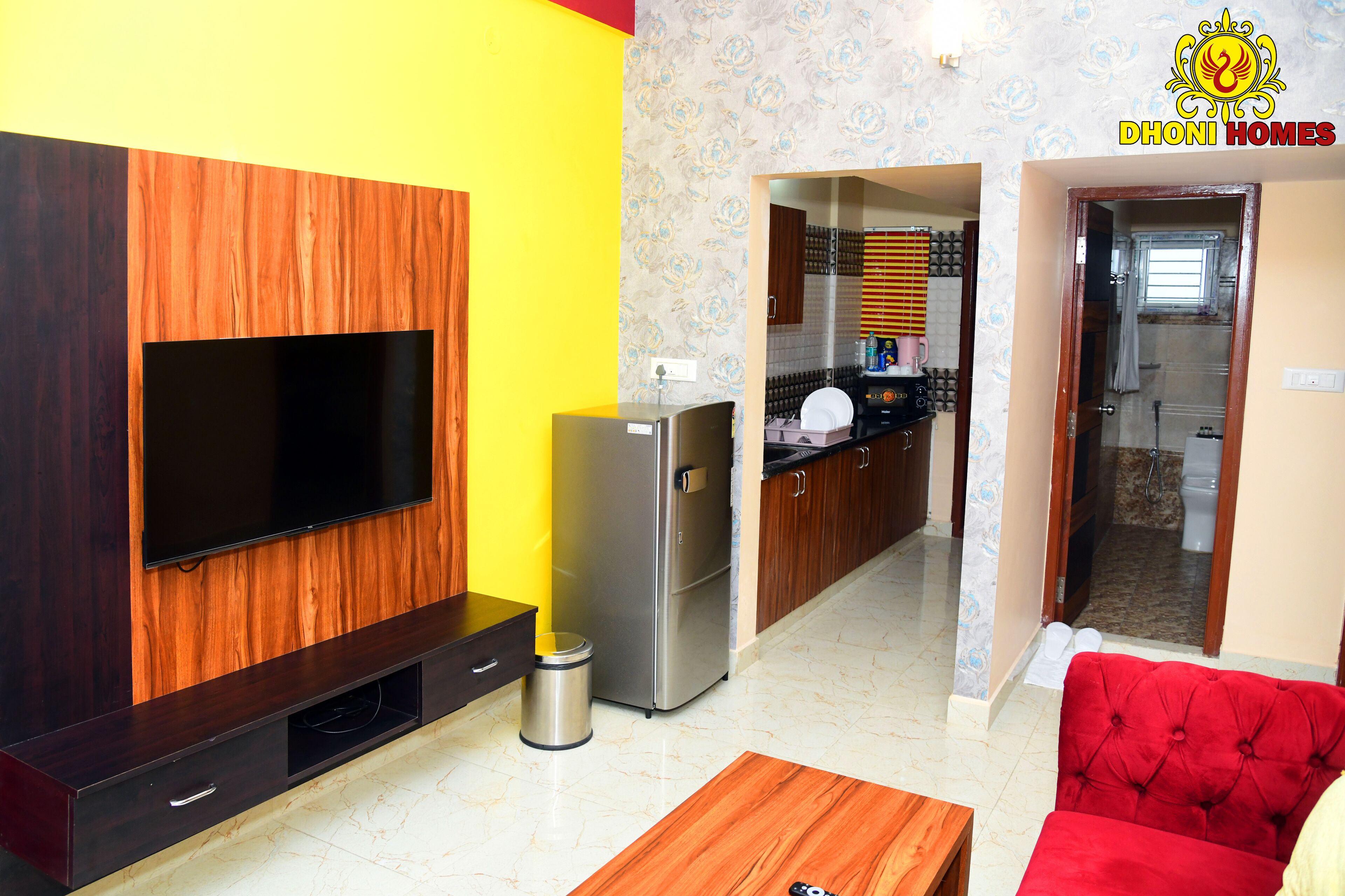 A living room with a flat-screen TV, a red sofa, and a wooden coffee table.