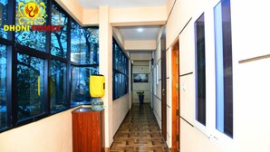 Un pasillo con ventanas amplias, un armario de madera y una planta en maceta.
