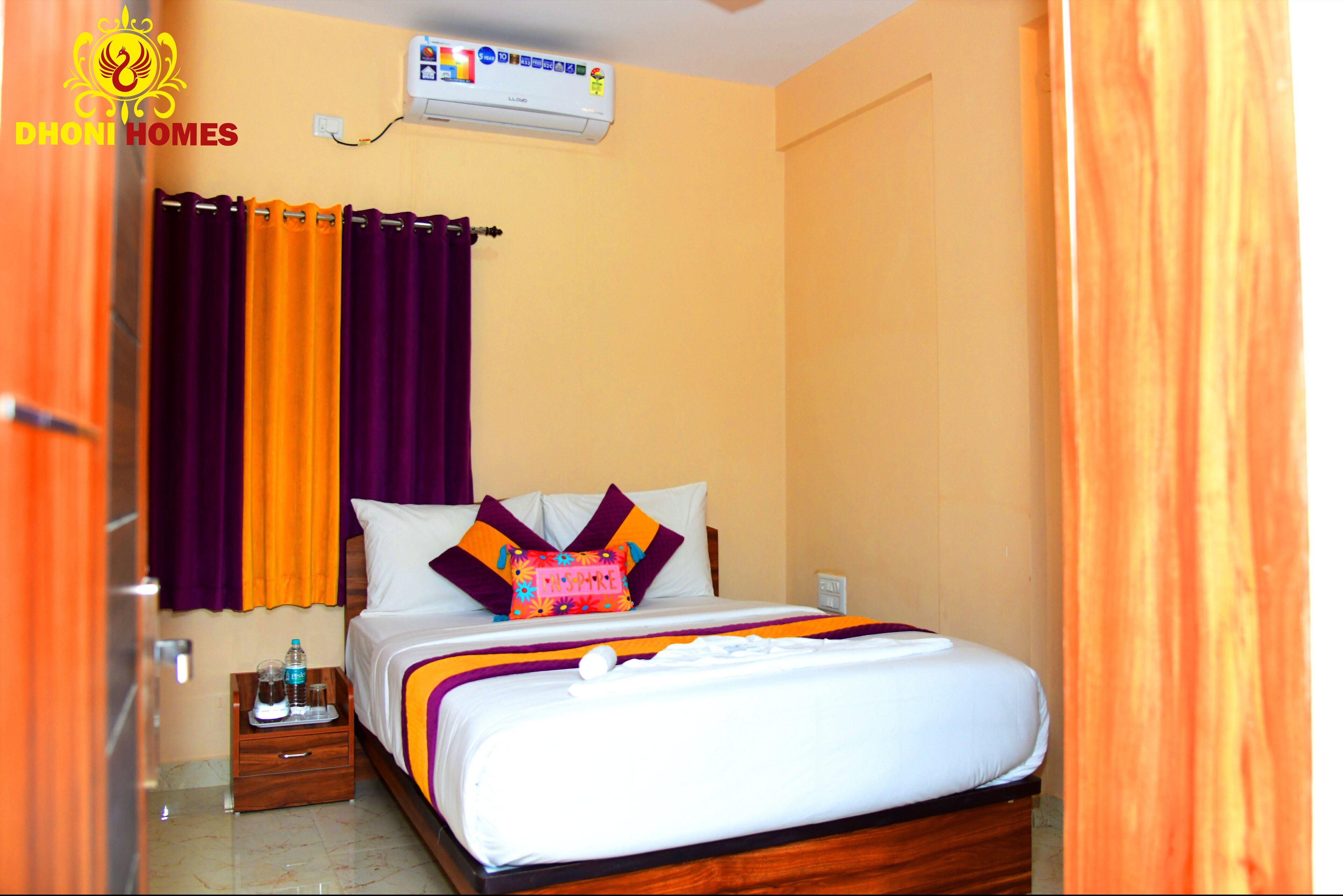 Una habitación de hotel con cama, cortinas, mesita de noche y aire acondicionado.