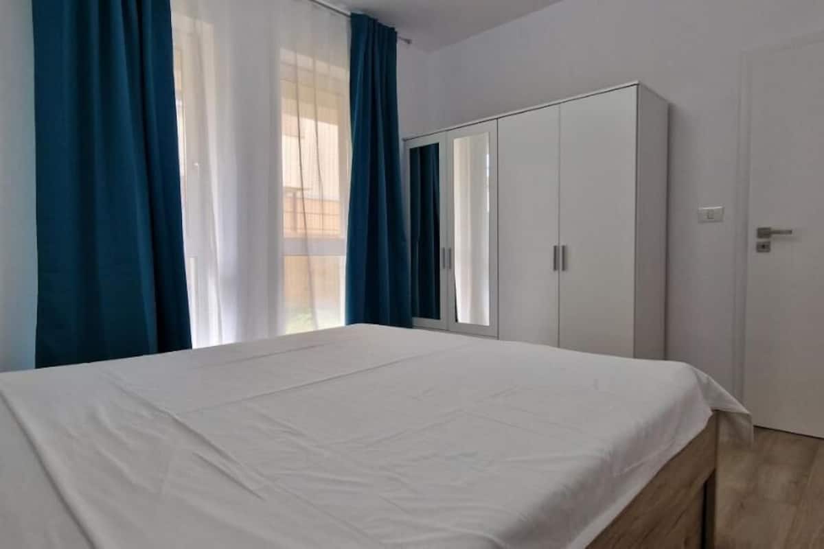 A bedroom with a bed, a wardrobe, and a door.