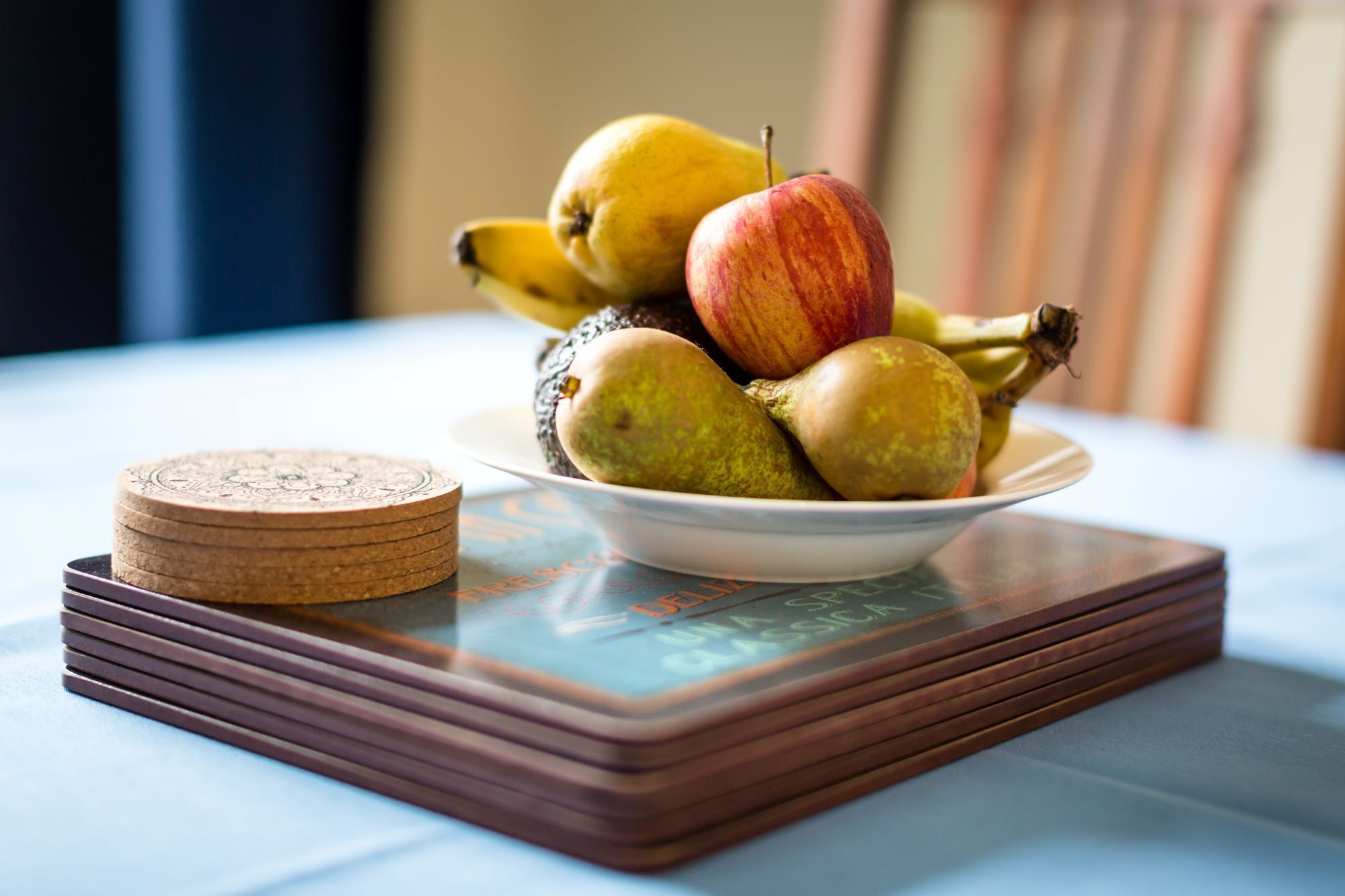 A bowl of fruit on a tray with a stack of coasters.