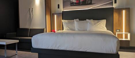 A modern hotel room with a large bed, a desk, and a wall-mounted TV.