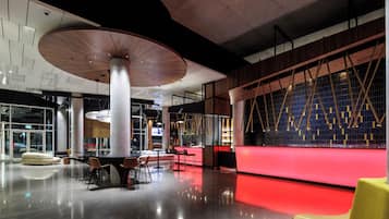A modern interior with a red-lit reception desk, high ceilings, and contemporary furniture.