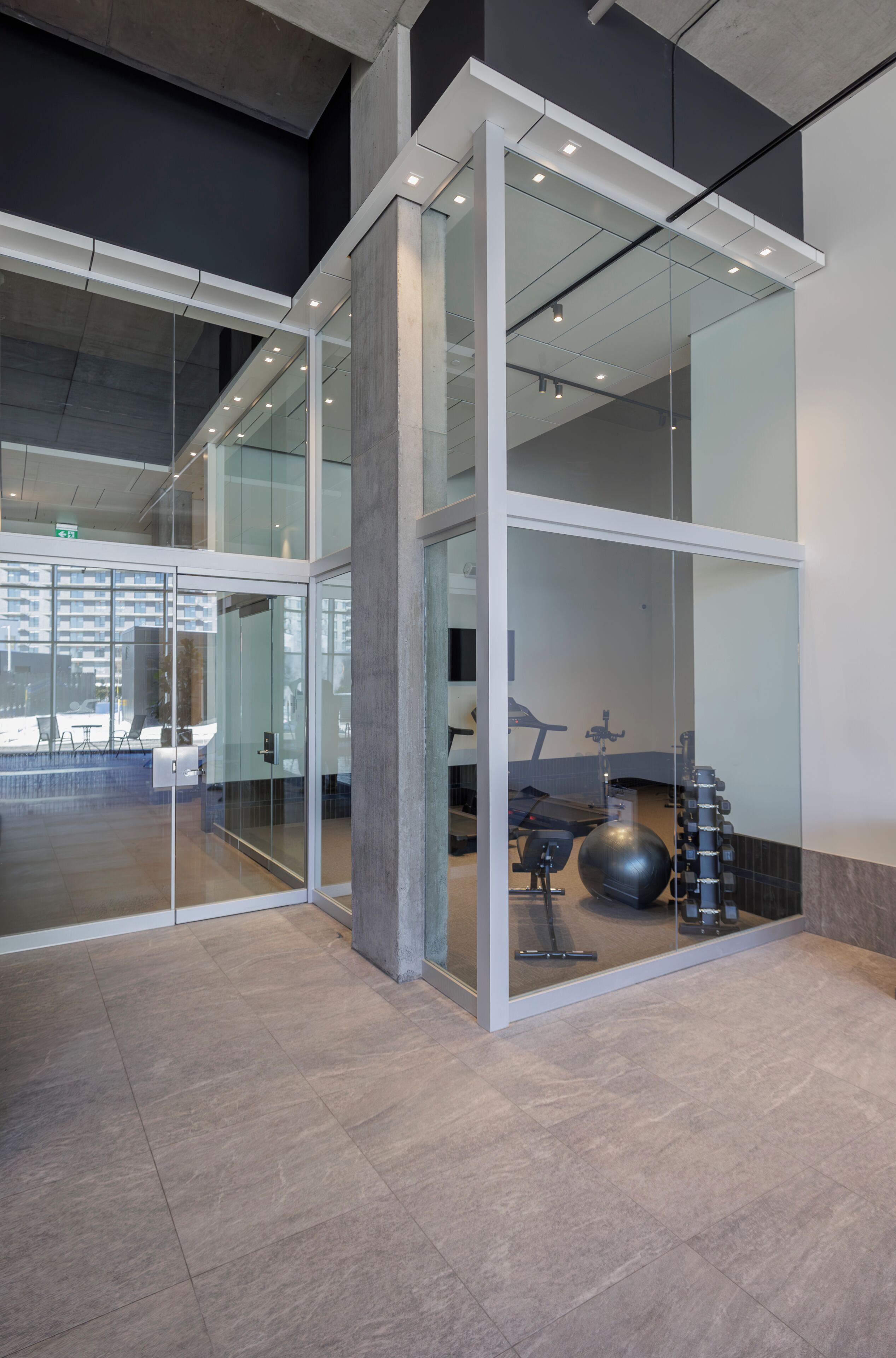 A modern interior with glass partitions, a visible exercise area with equipment, and a clean, minimalist design.