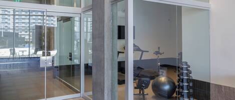 A modern interior with glass partitions, a visible exercise area with equipment, and a clean, minimalist design.