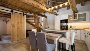 A rustic kitchen with wooden beams, a staircase, and a dining area with chairs. - Ferienwohnung Josefine (Münster Albachten)