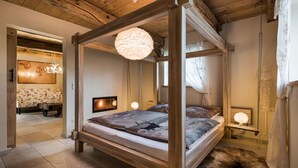 A four-poster bed with a wooden frame and a fluffy white lamp hanging above it. - Ferienwohnung Josefine (Münster Albachten)