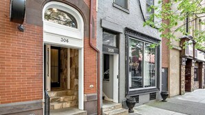 A brick building with a white door labeled "306" and a black storefront with a large window.