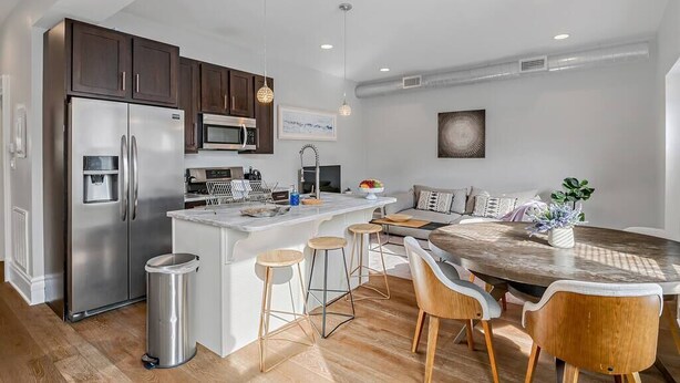A modern kitchen with a central island, stainless steel appliances, and wooden bar stools.