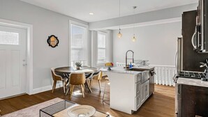 A modern kitchen with a central island, white cabinetry, and pendant lighting.