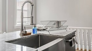 A kitchen with a modern faucet, a sink, and a wire basket on the countertop.