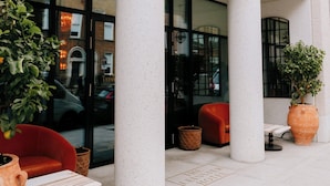 The exterior of The Leinstier hotel with large columns, a red chair, and potted plants. - The Leinster (Dublin)