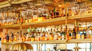 A bar area with a marble countertop, various bottles, glasses, and a gold-colored lamp. - The Leinster (Dublin)