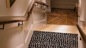 A staircase with a black and white patterned rug, wall-mounted artwork, and modern lighting fixtures.