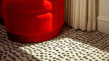 Um sofá vermelho com uma almofada estampada, um banco branco e um tapete padronizado.