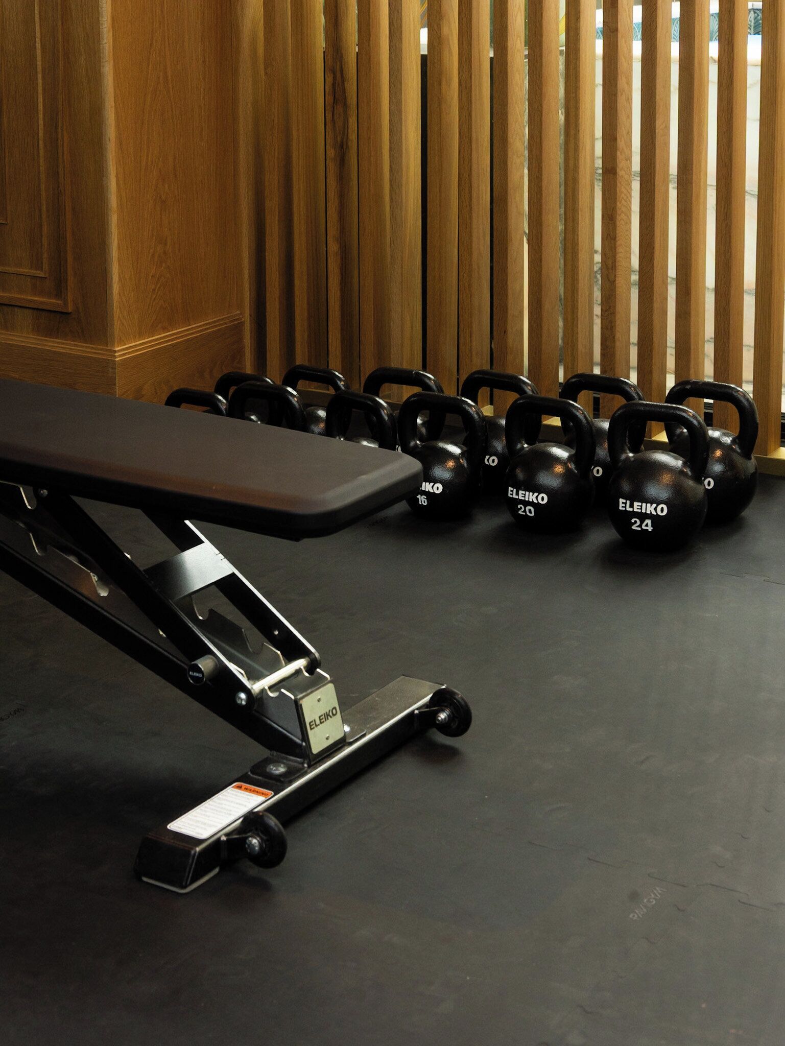 Une salle de sport équipée d’un banc et de kettlebells.