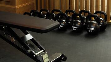 Une salle de sport équipée d’un banc et de kettlebells.